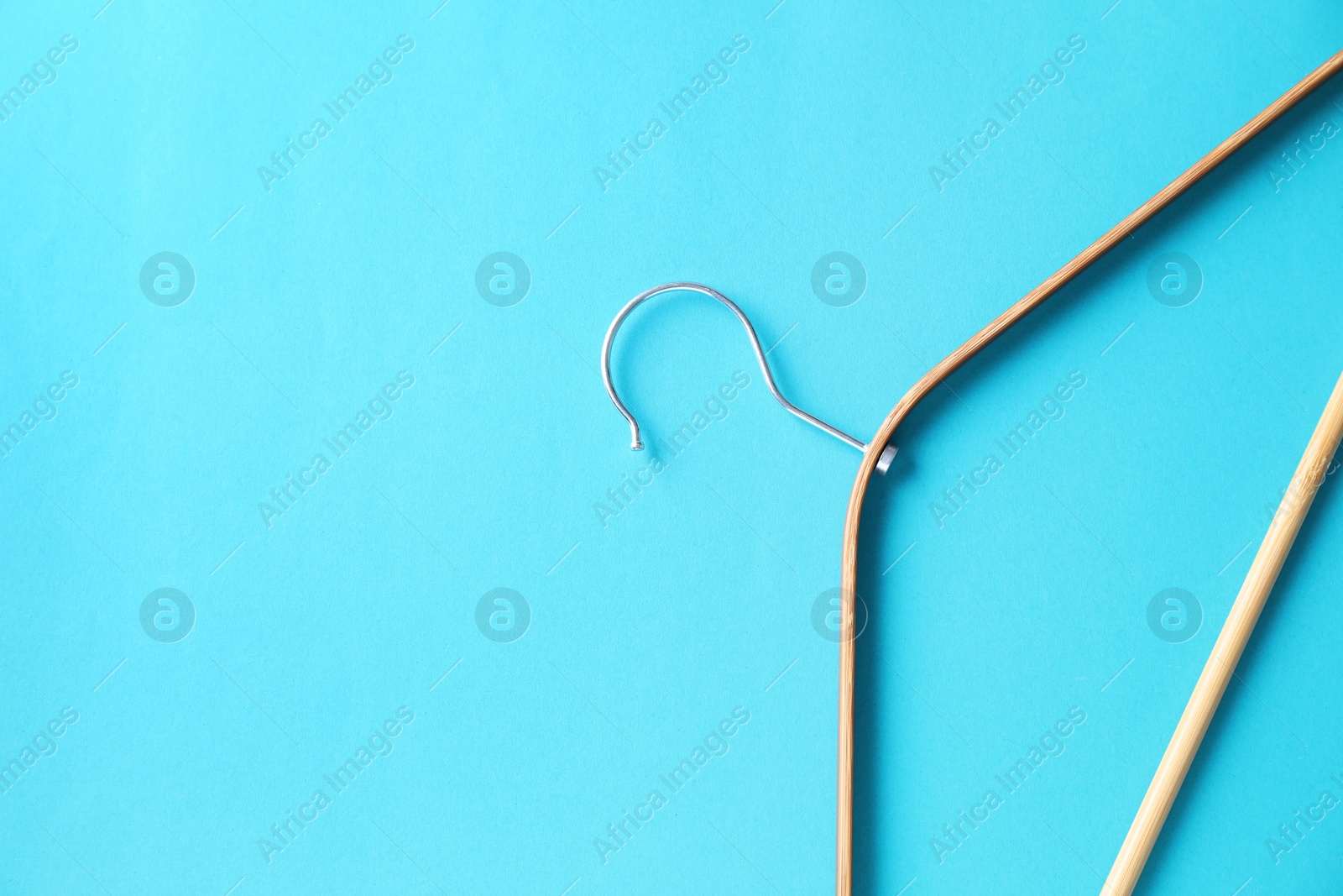 Photo of One wooden hanger on light blue background, top view. Space for text