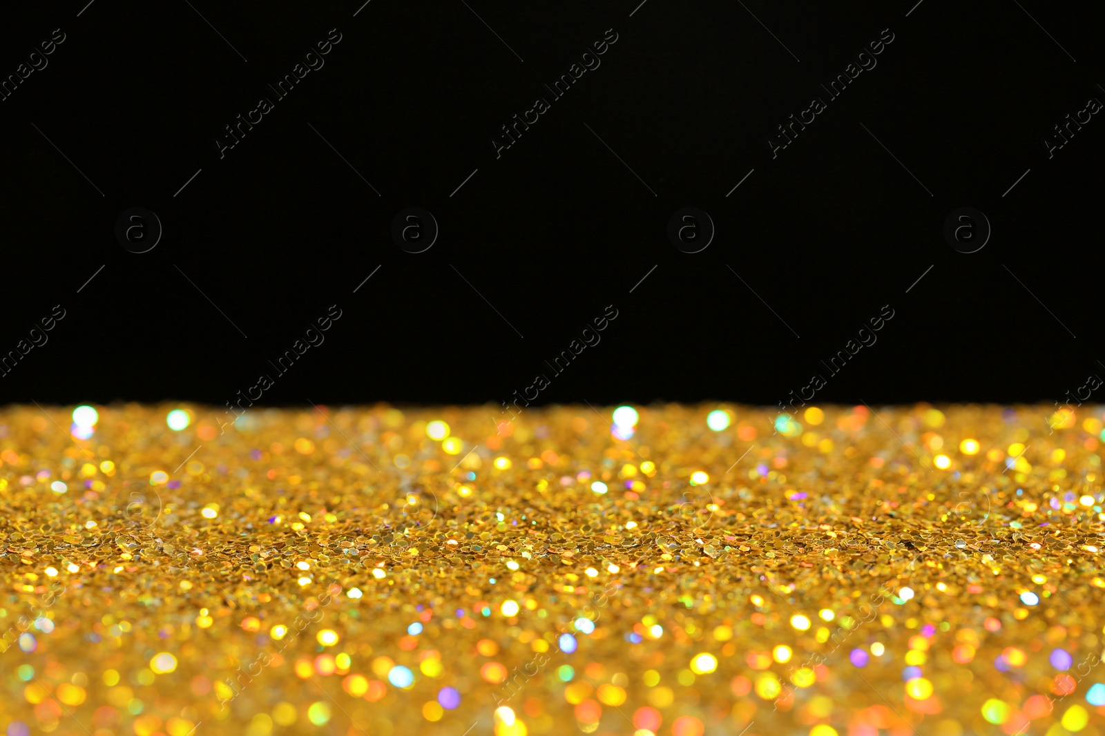 Photo of Many golden paillettes against black background. Space for text
