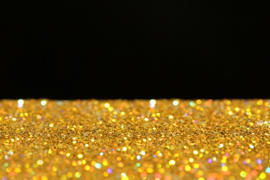 Many golden paillettes against black background. Space for text