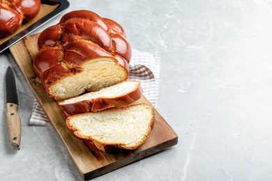 Photo of Cut homemade braided bread on grey table, space for text. Traditional Shabbat challah