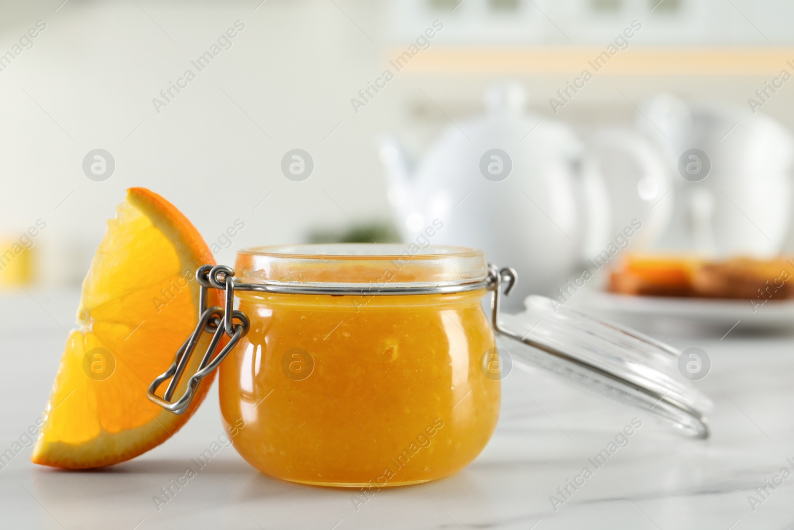 Photo of Delicious orange marmalade and citrus fruit slice on white marble table