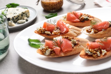 Photo of Tasty bruschettas with salmon and blue cheese served on table