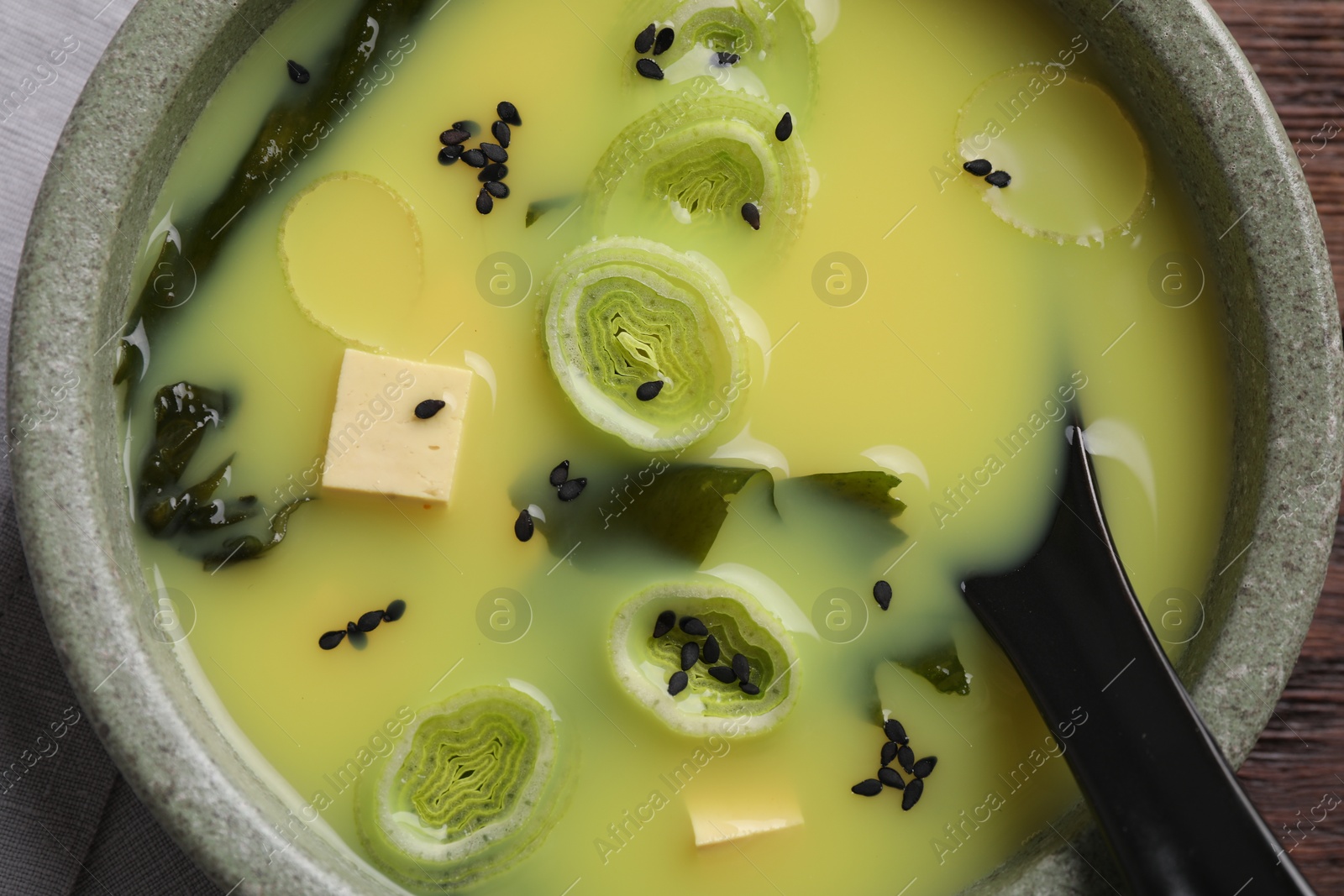 Photo of Bowl of delicious miso soup with tofu and spoon, top view