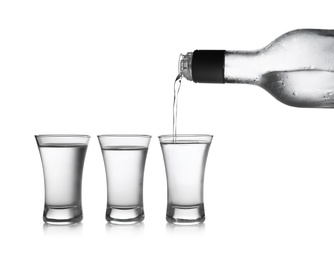 Pouring cold vodka into shot glass on white background