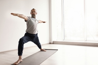 Photo of Sporty man practicing yoga indoors