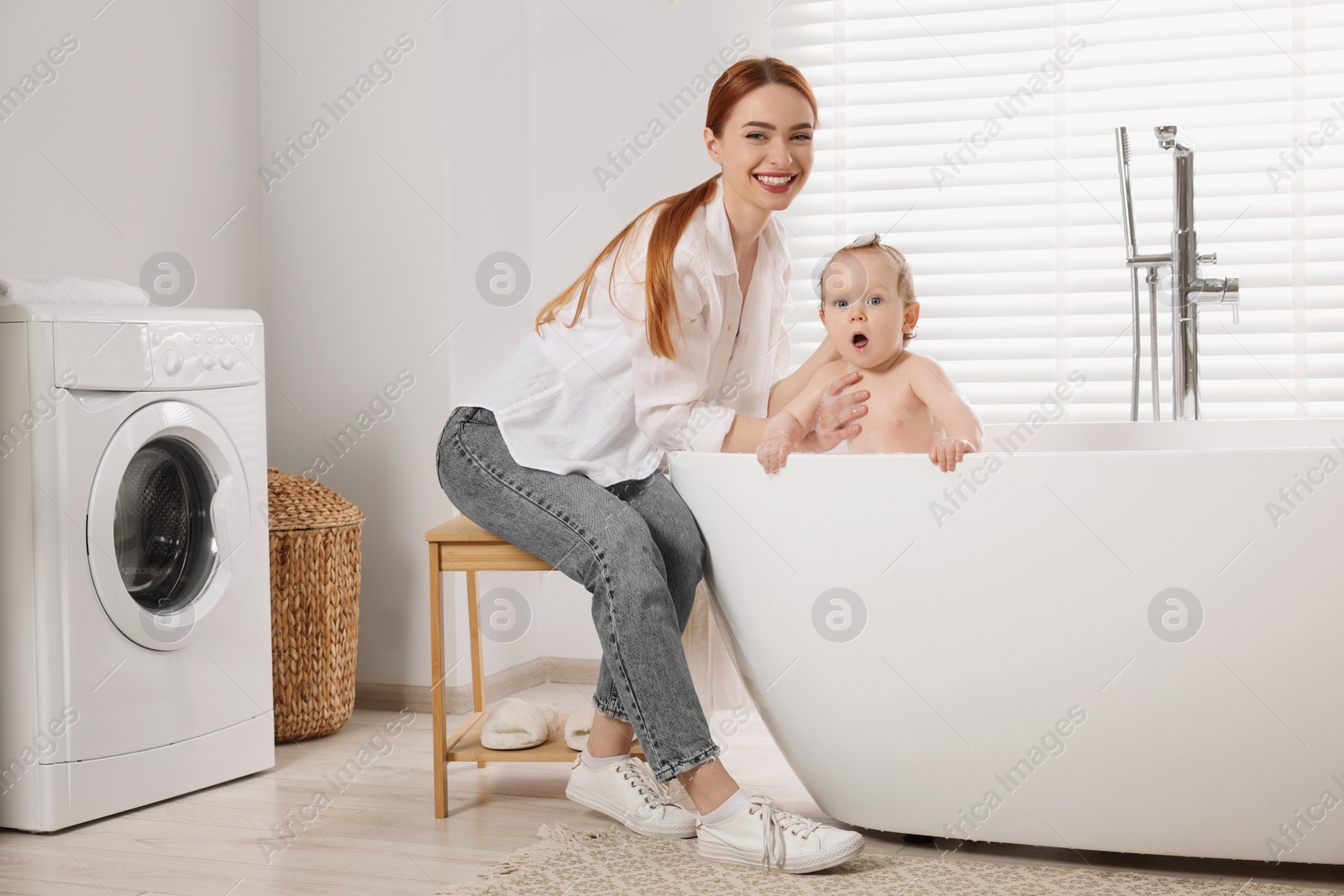 Photo of Mother washing her little baby in tub at home