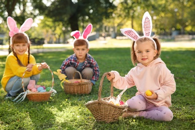 Cute little children hunting eggs in park. Easter tradition