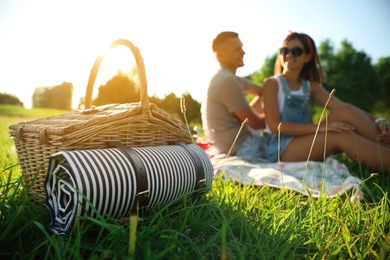 Photo of Happy couple on picnic in park, focus on basket