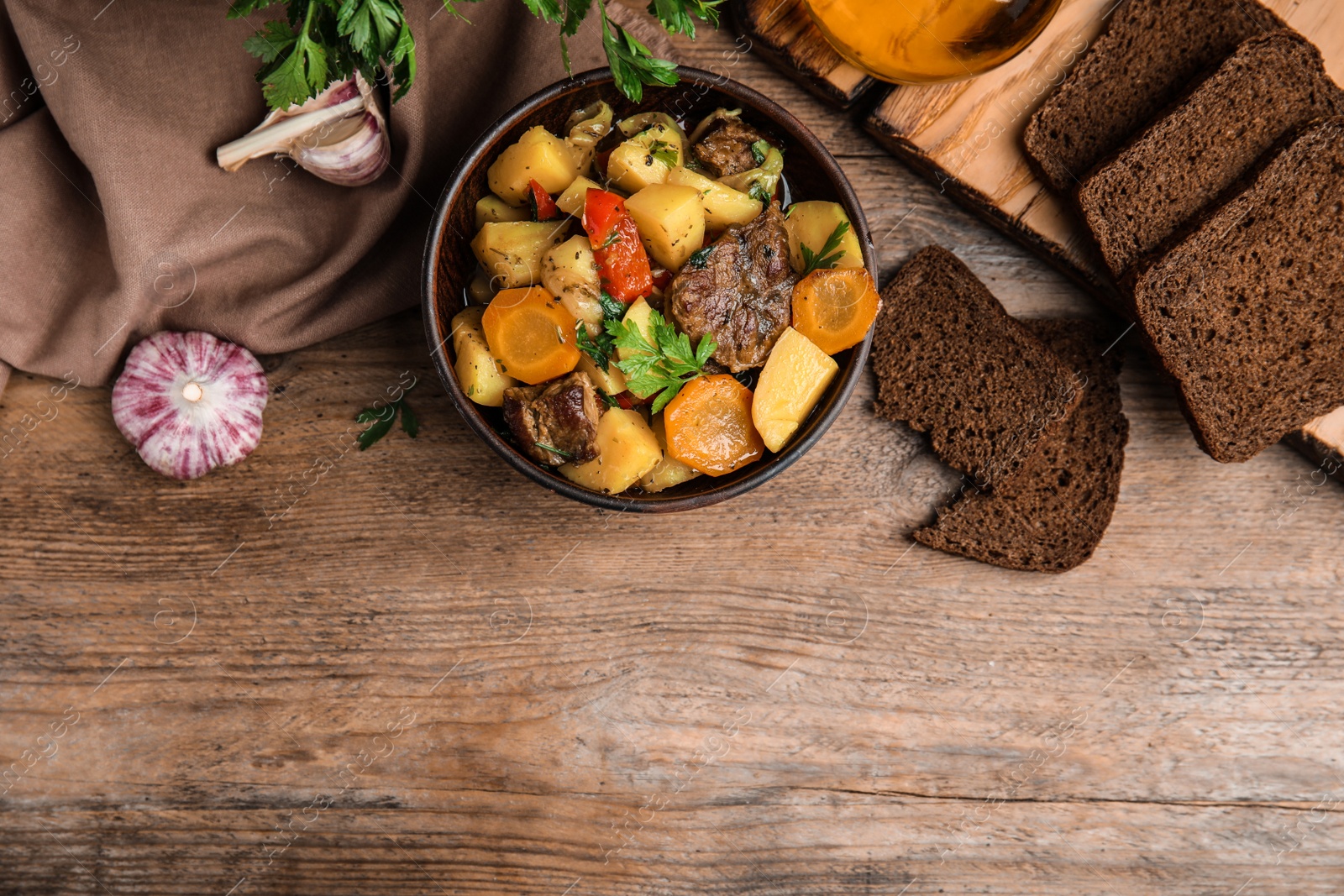 Photo of Tasty cooked dish with potatoes in earthenware served on wooden table, flat lay. Space for text