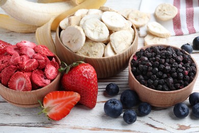Photo of Different freeze dried and fresh fruits on white wooden table, closeup