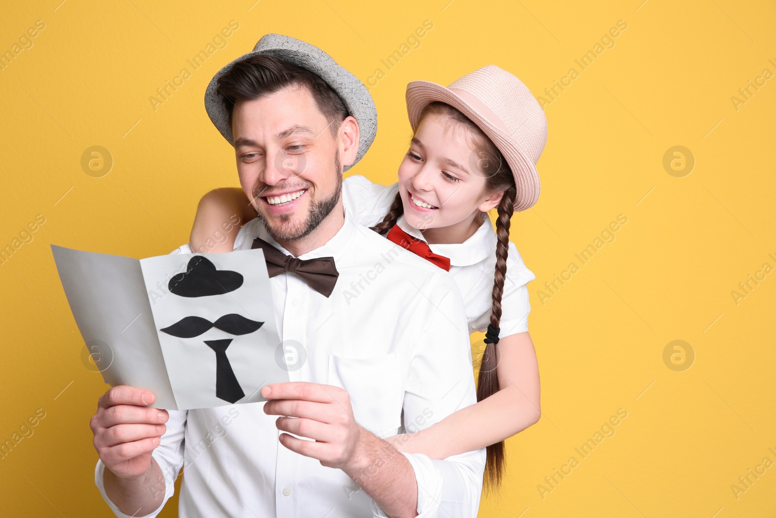 Photo of Little girl and her dad with greeting card for Father's Day on color background