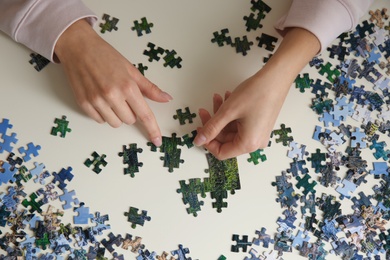 Young woman playing with puzzles at table, top view