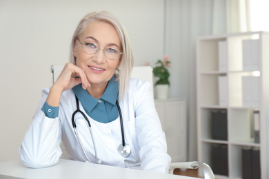 Portrait of mature female doctor in white coat at workplace