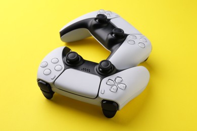 Photo of Two wireless game controllers on yellow background