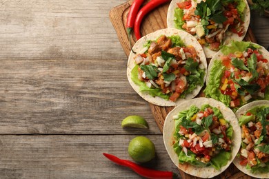 Photo of Delicious tacos with vegetables, meat and lime on wooden table, flat lay. Space for text