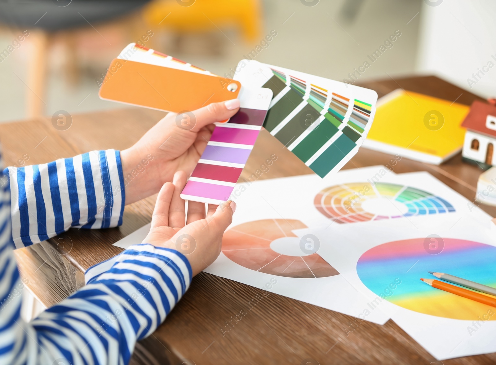 Photo of Female designer working with color palette samples at table