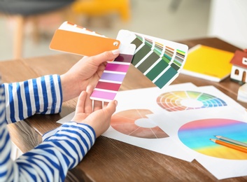 Photo of Female designer working with color palette samples at table