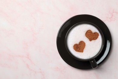 Photo of Cup of aromatic coffee with heart shaped decoration on pink marble table, top view. Space for text