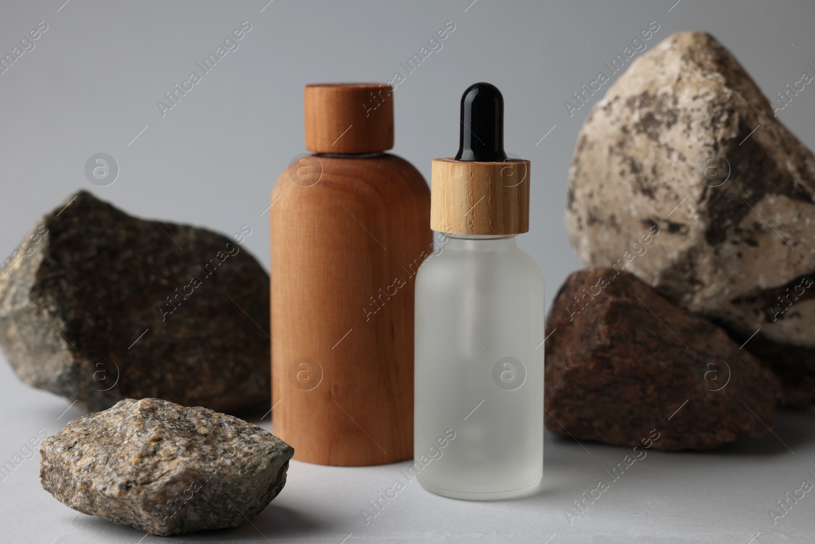 Photo of Different bottles and stones on grey background, closeup