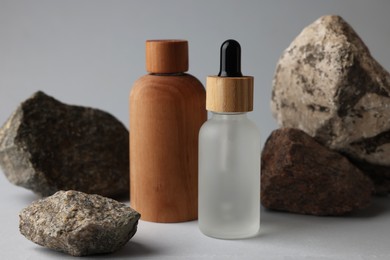 Different bottles and stones on grey background, closeup