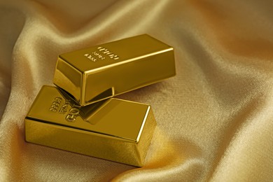 Photo of Gold bars on shiny silk fabric, closeup