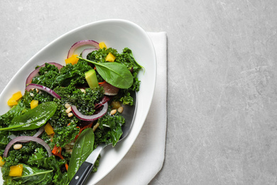 Photo of Tasty fresh kale salad on light grey table, top view