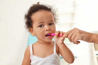 Photo of Woman and her African-American daughter with toothbrush on blurred background