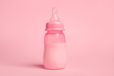 Photo of One feeding bottle with milk on pink background