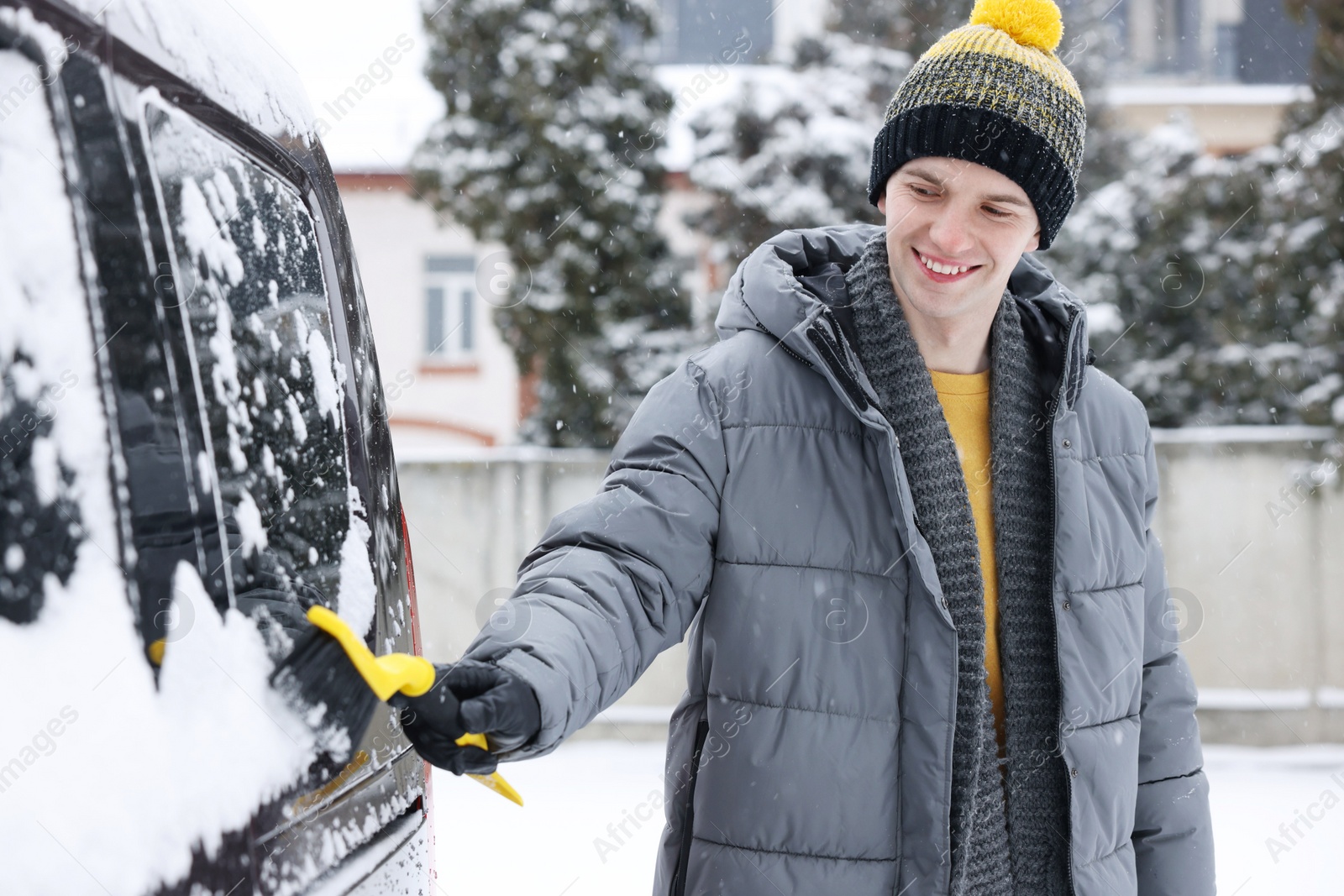 Photo of Man cleaning snow from car window outdoors