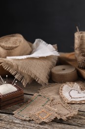 Pieces of burlap fabric and pincushion on wooden table, space for text