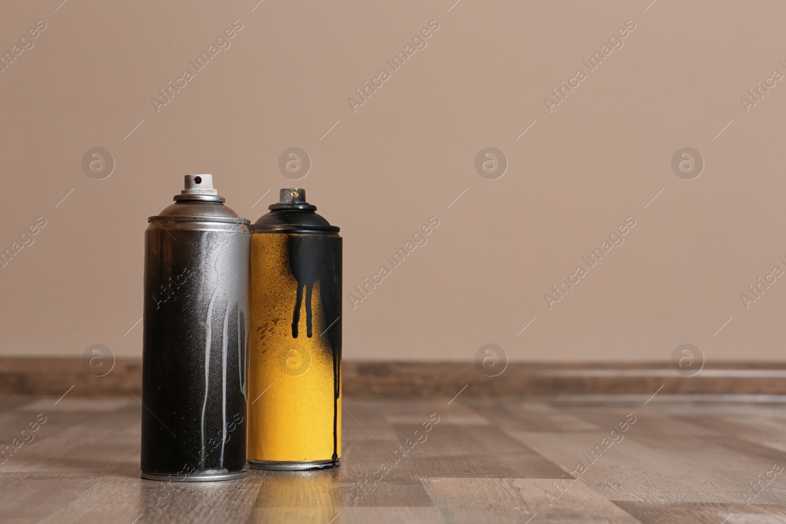 Photo of Used cans of spray paint on floor indoors. Space for text