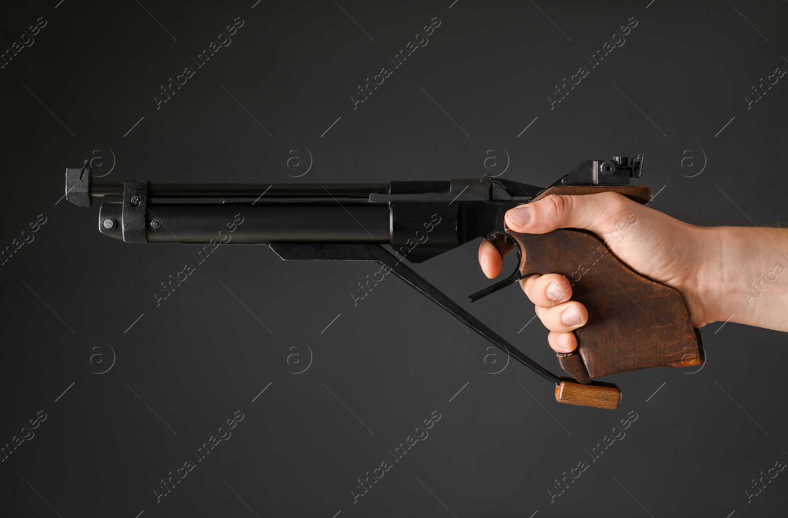 Photo of Gun shooting sport. Man aiming standard pistol on dark background, closeup