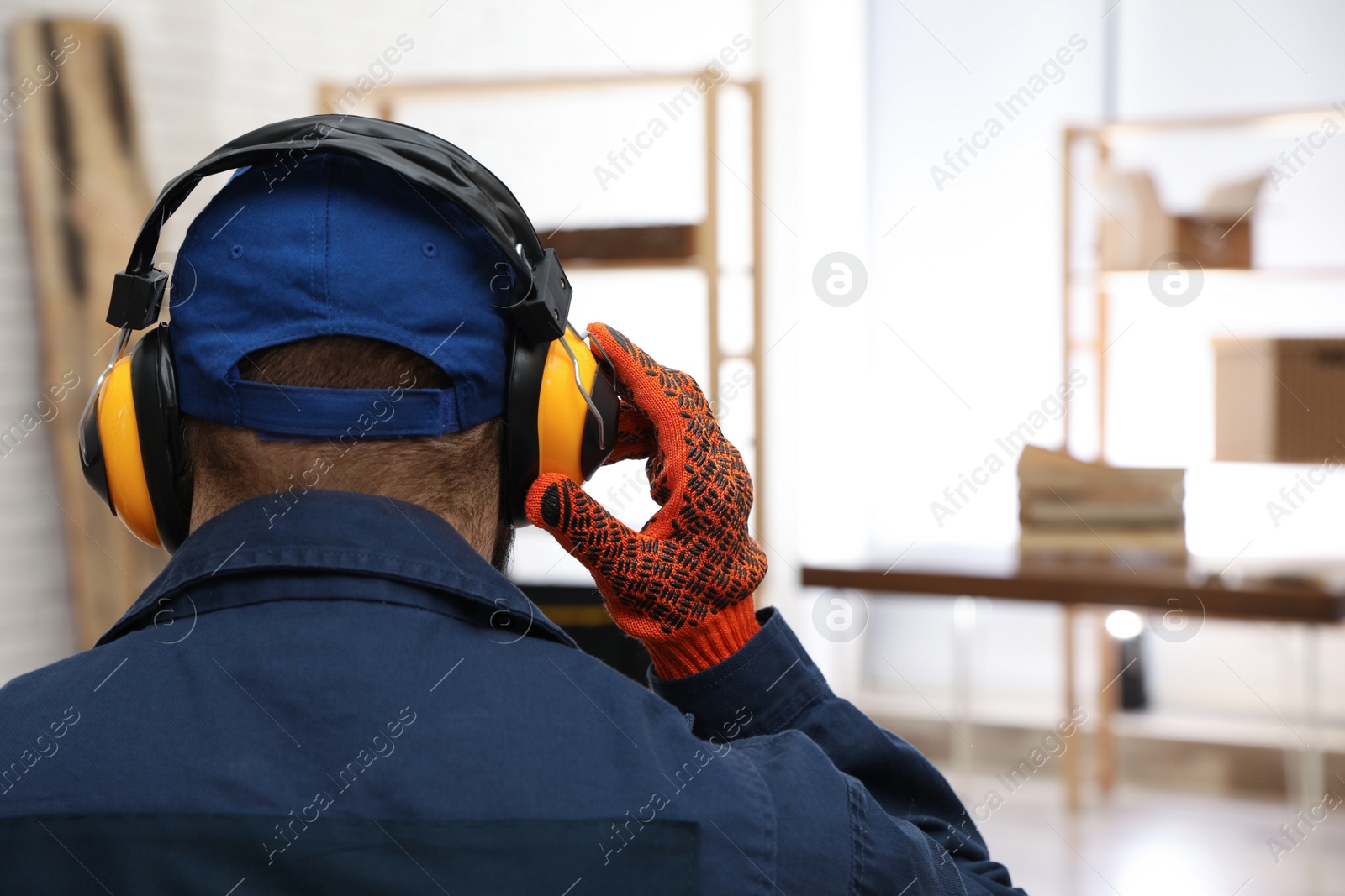 Photo of Worker wearing safety headphones indoors, back view. Hearing protection device