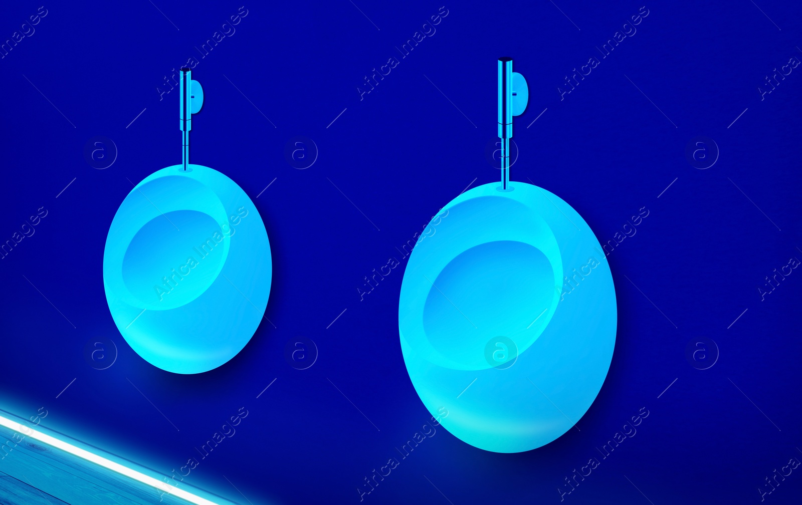 Image of Ceramic urinals in men's public restroom lit with UV blue light