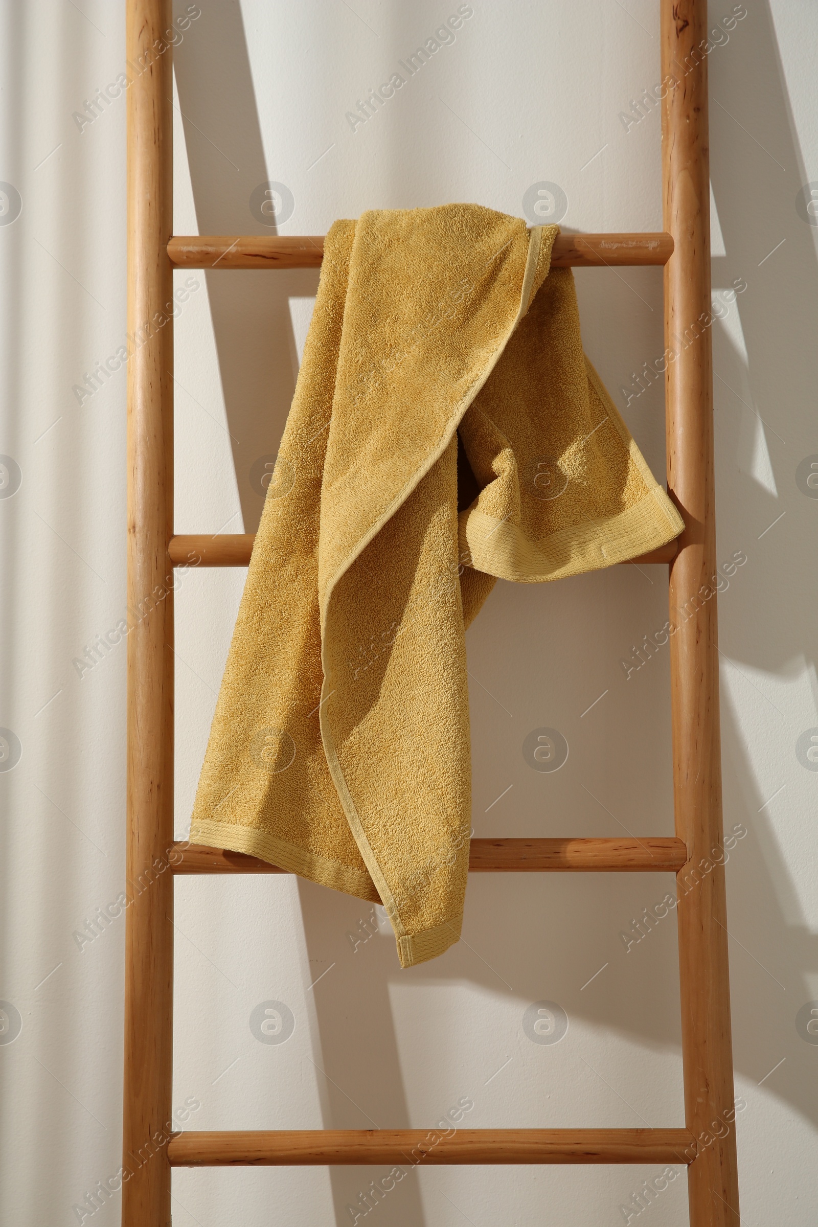 Photo of Yellow towel hanging on wooden ladder indoors