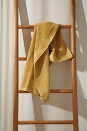 Photo of Yellow towel hanging on wooden ladder indoors