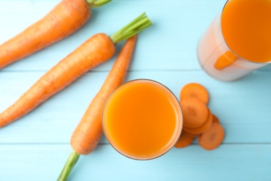 Photo of Glasses with carrot juice and fresh vegetable on wooden table, top view