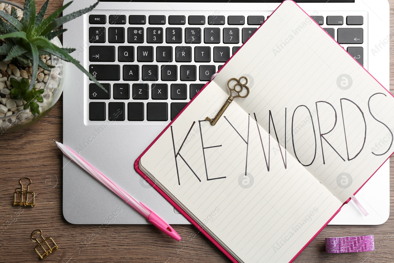 Photo of Notebook with word KEYWORDS, vintage key and laptop on wooden table, flat lay