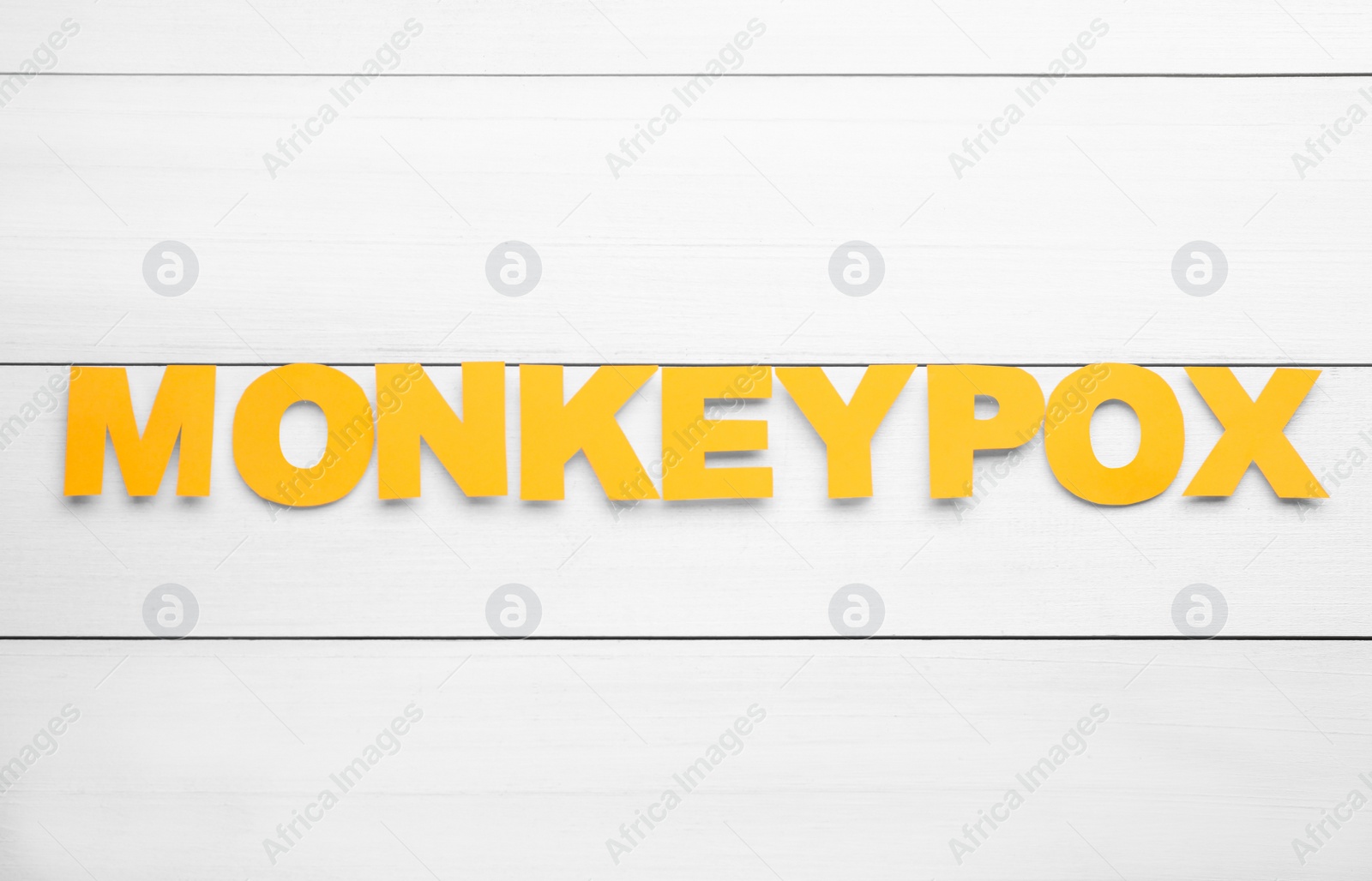 Photo of Word Monkeypox made of bright letters on white wooden table, top view