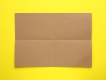 Sheet of brown paper on yellow background, top view