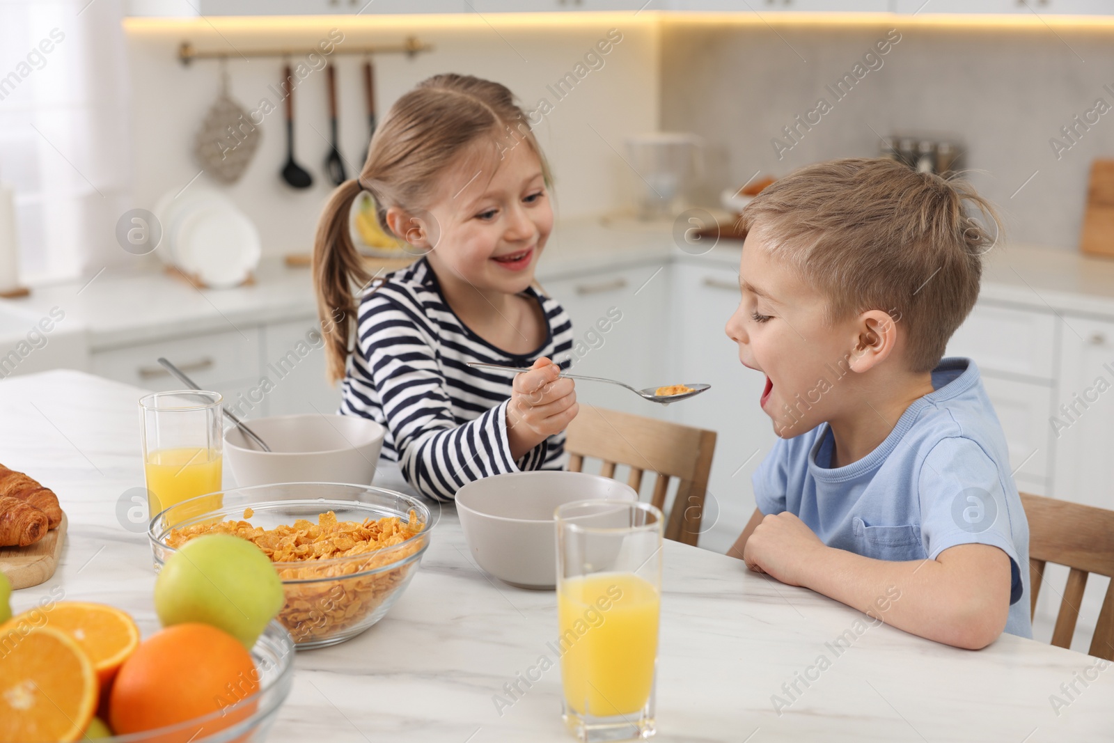 Photo of Little children having breakfast at table in kitchen