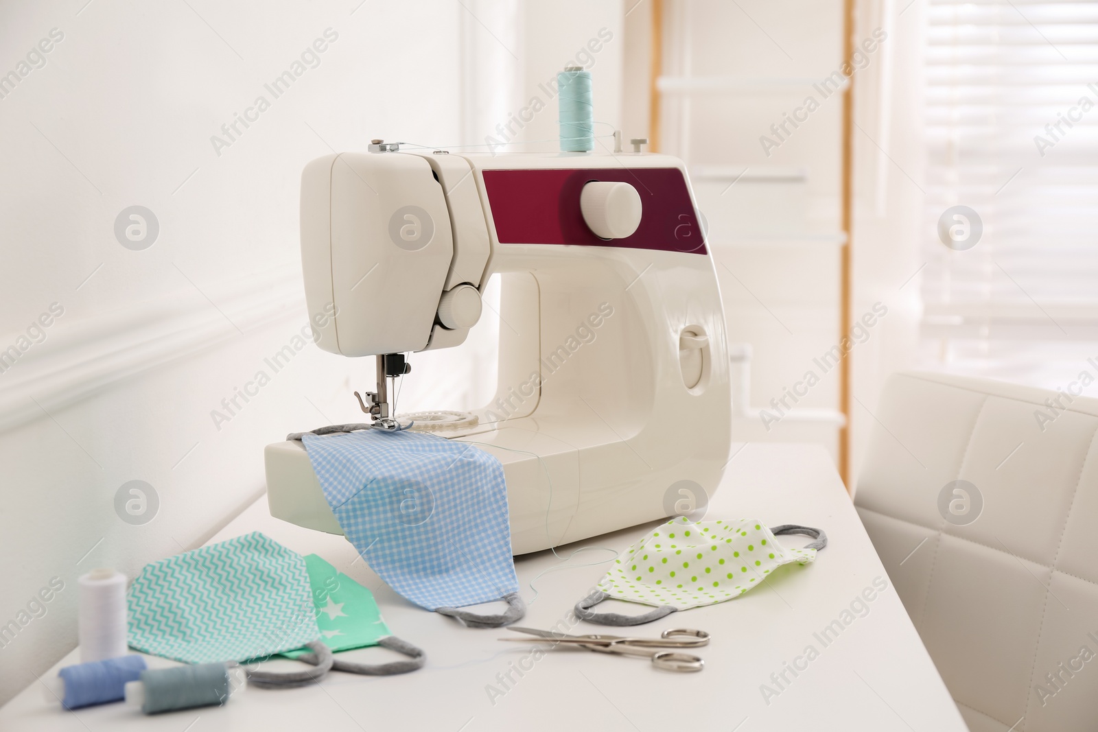 Photo of Sewing machine with cloth mask on table indoors, space for text