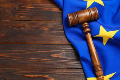 Photo of Judge's gavel and flag of European Union on wooden table, flat lay. Space for text