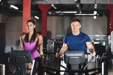 Photo of Couple working out on elliptical trainers in gym