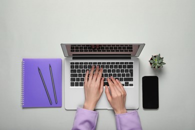 Woman using laptop at light table, top view