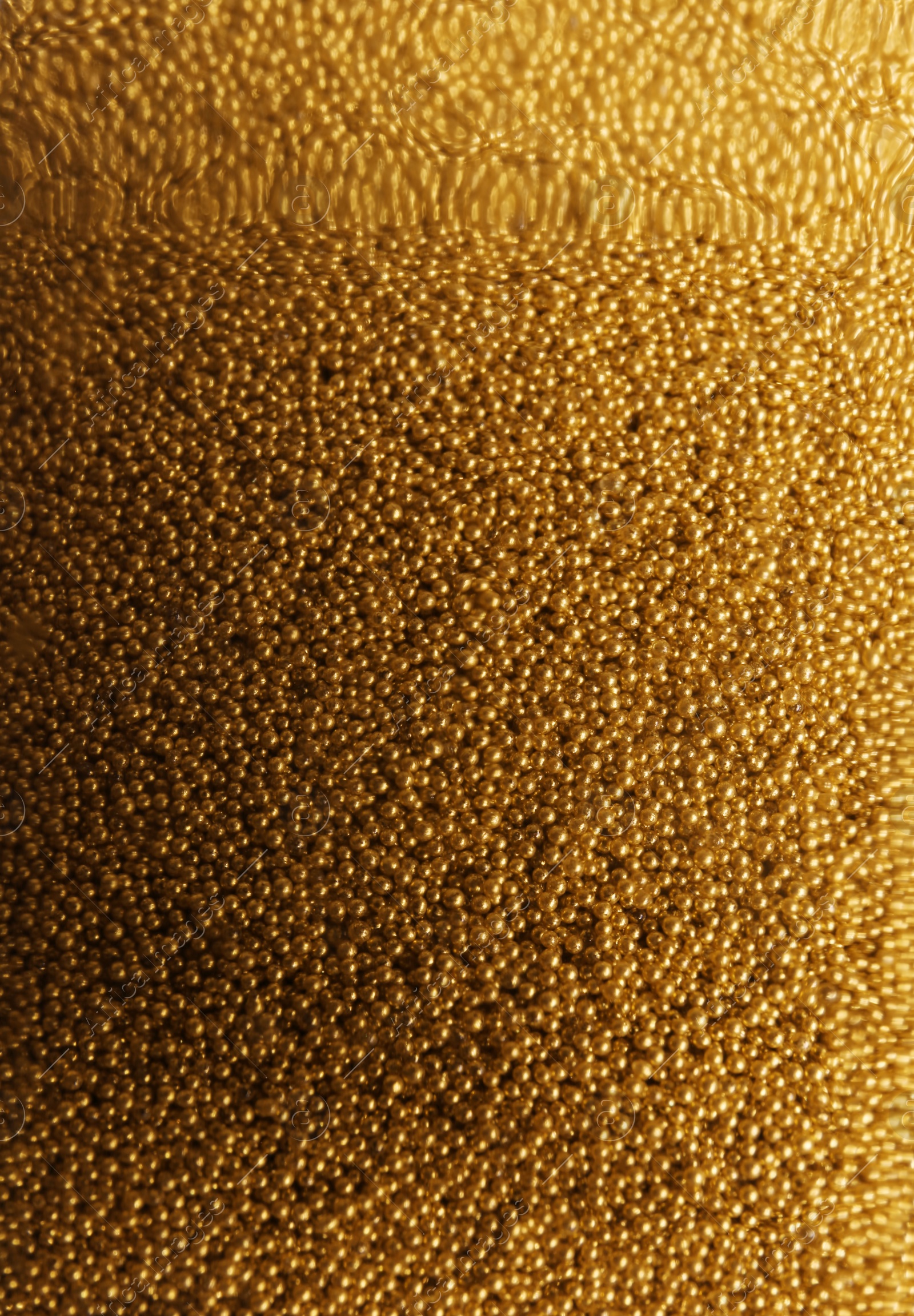 Photo of Many gold beads as background, view through glass