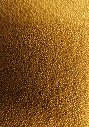 Photo of Many gold beads as background, view through glass