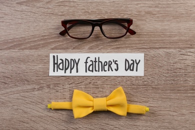 Photo of Bow tie and glasses on wooden background. Father's day celebration