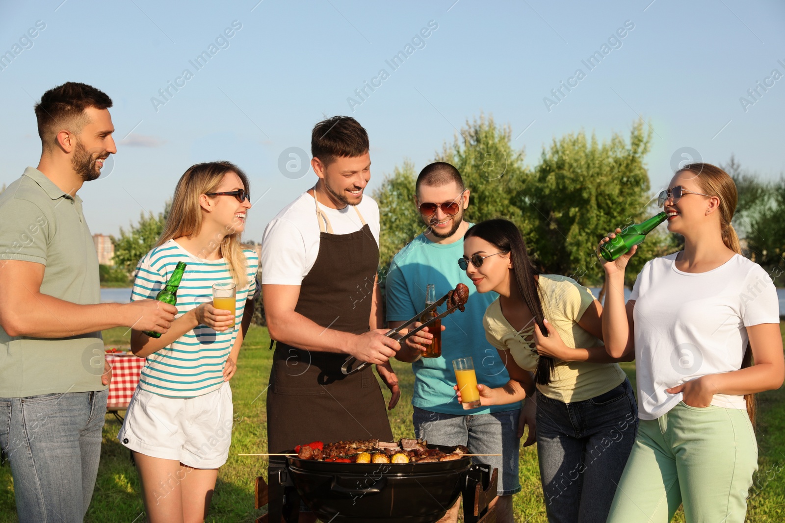 Photo of Group of friends cooking food on barbecue grill in park