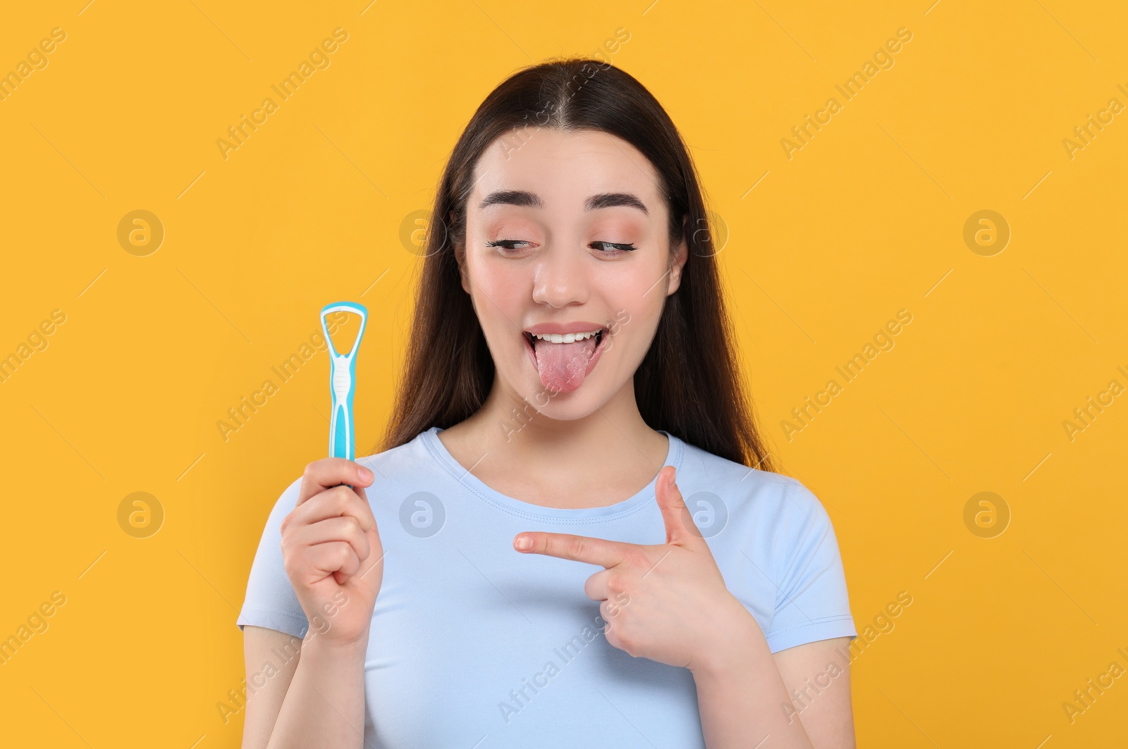 Photo of Happy woman showing tongue cleaner on yellow background